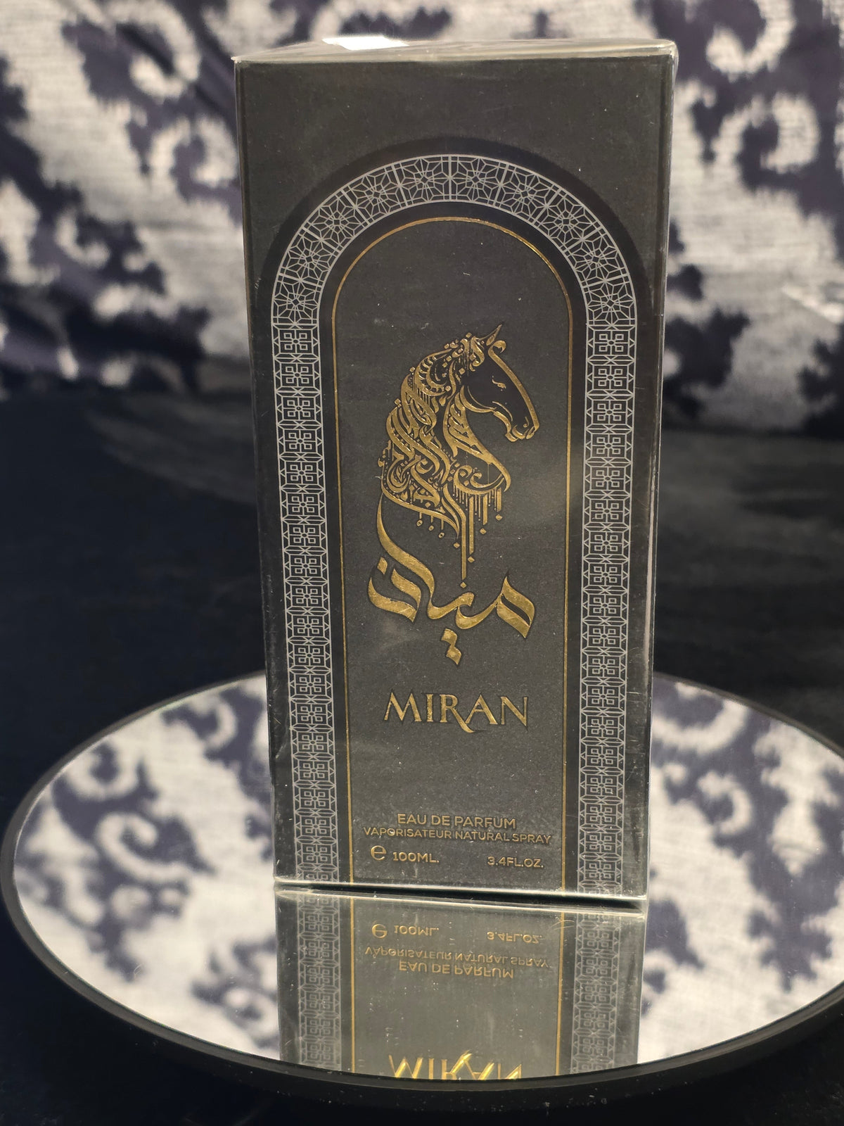 Miran Eau de Parfum 100mL box - sleek matte black packaging with intricate silver Islamic geometric lattice border, Moorish arch panel featuring gold Arabian unicorn calligraphy and MIRAN typography