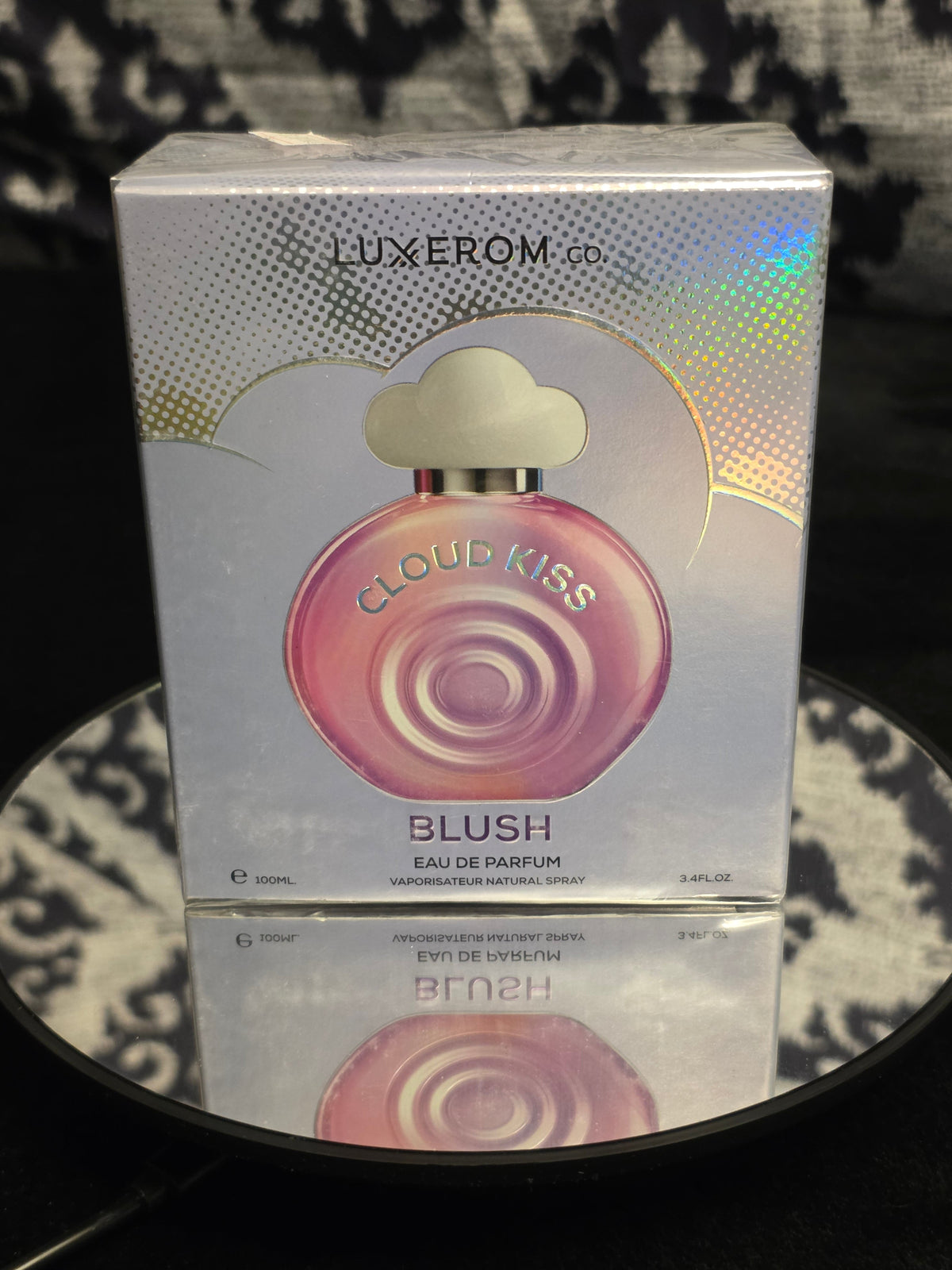 Luxxerom Co. Cloud Kiss Blush Eau de Parfum 100mL box - holographic iridescent silver packaging with iconic round blush pink swirl orb bottle and cloud cap artwork