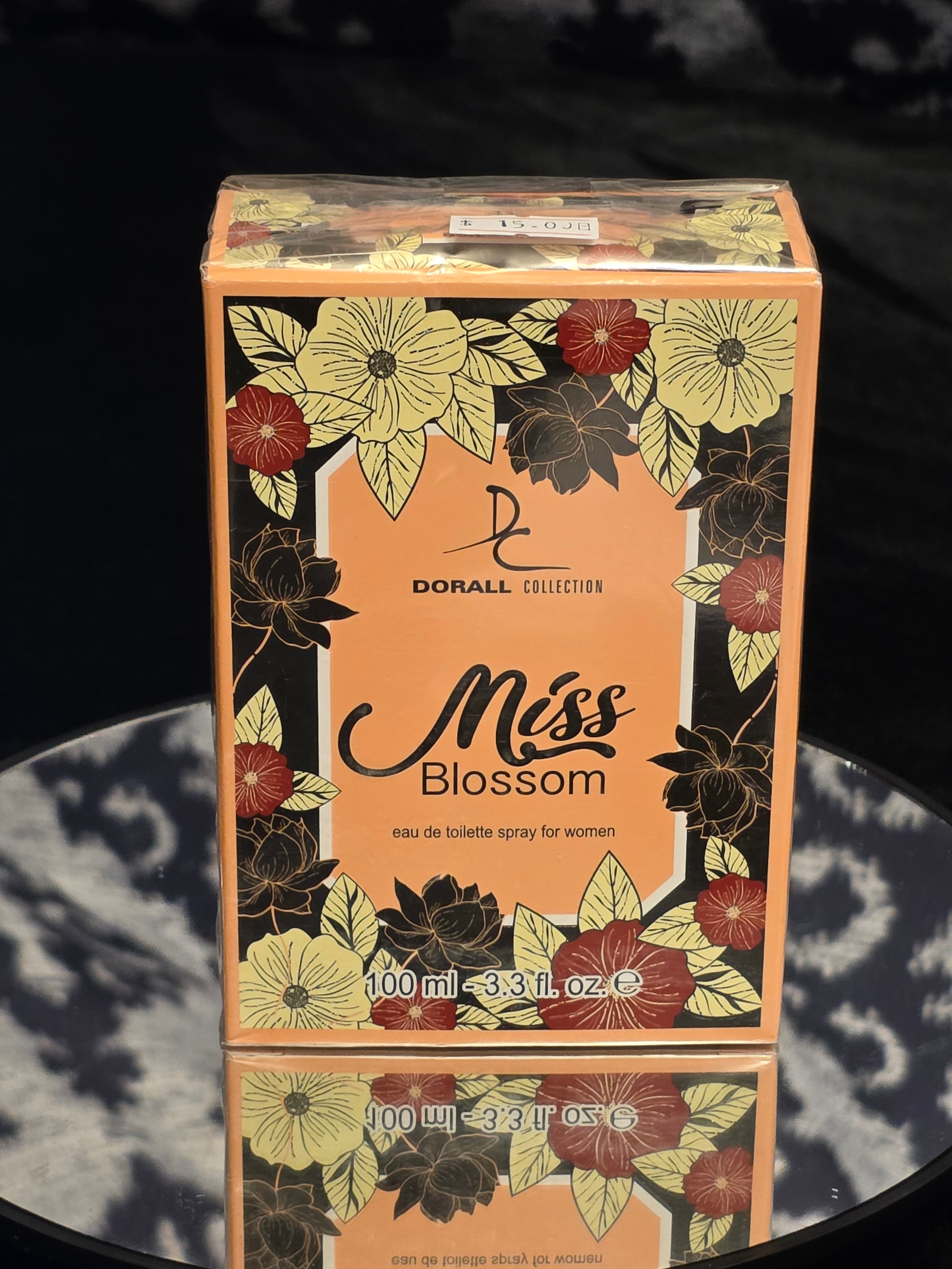 Dorall Collection Miss Blossom Eau de Toilette 100mL box - warm amber orange packaging with rich black floral botanical artwork featuring cream yellow and deep red blossoms