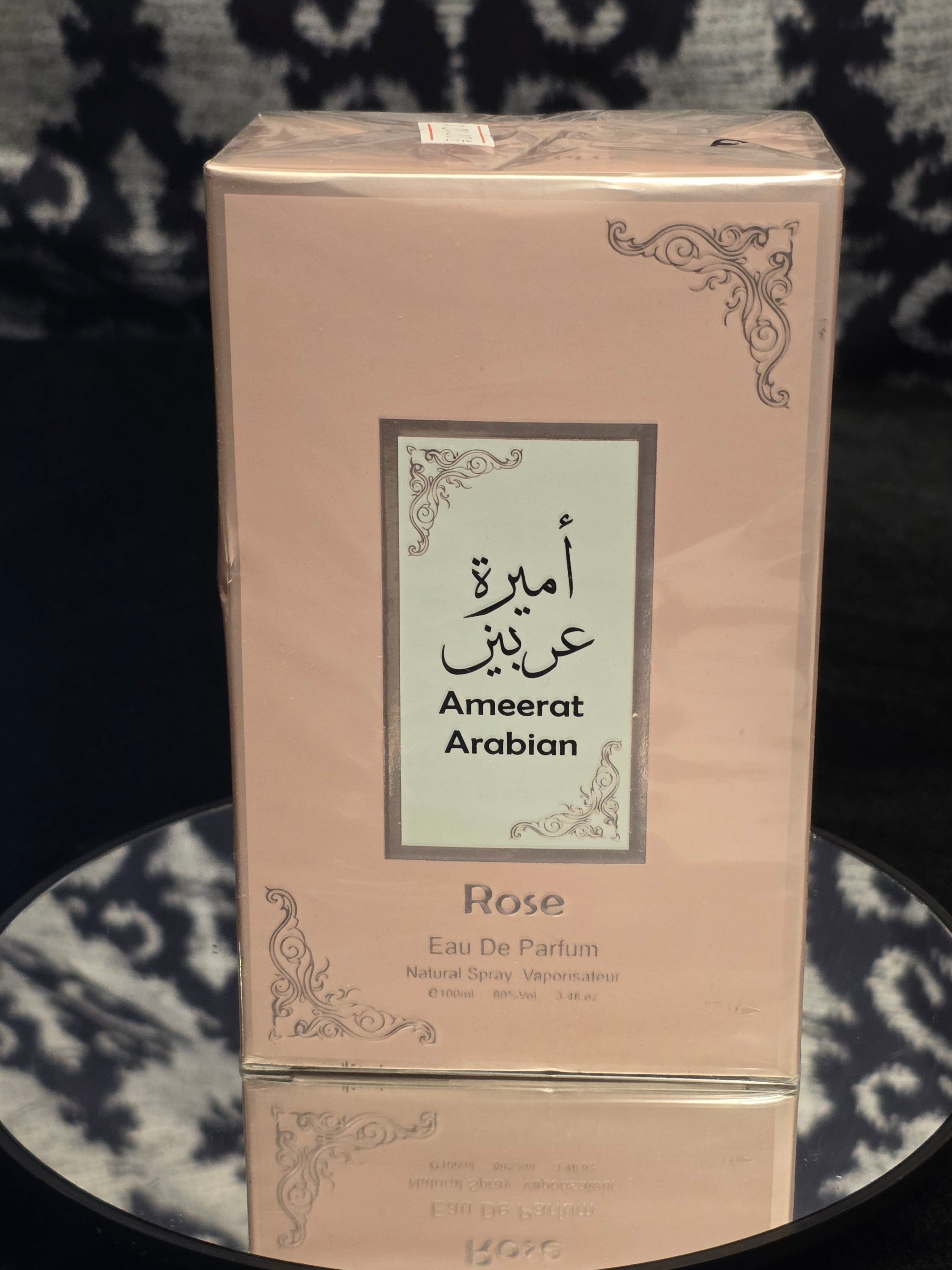 Ameerat Arabian Rose Eau de Parfum 100mL box - soft blush pink packaging with silver filigree corner detail and Arabic calligraphy label